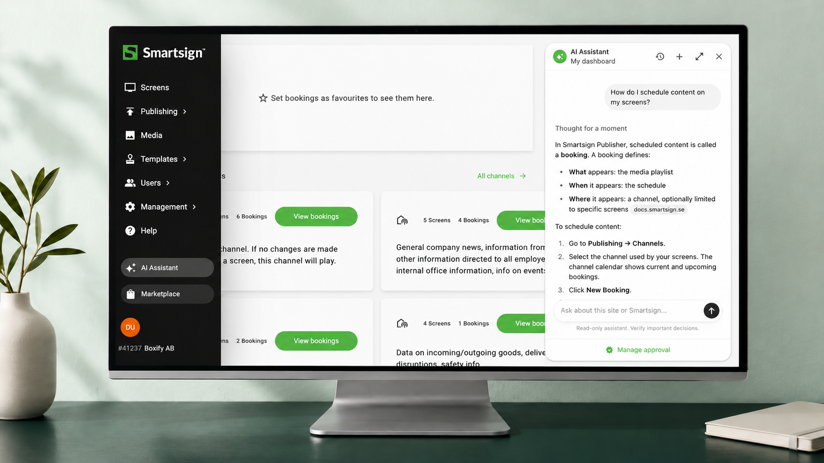 Smartsign Publisher with the AI assistant open on a desktop monitor in a bright workspace.